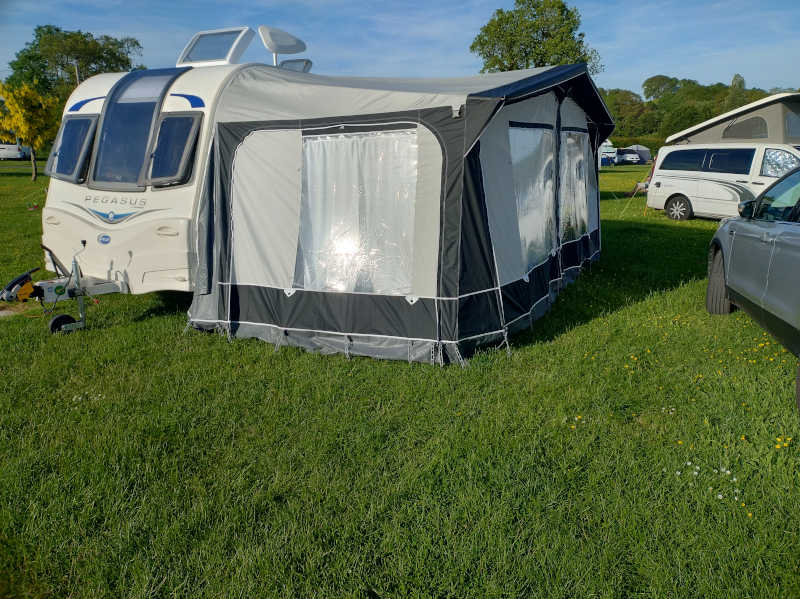 A caravan with an awning attached in bright sunlight